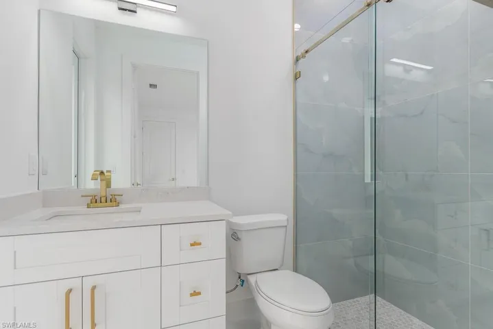 Bathroom featuring a shower with door, vanity, and toilet