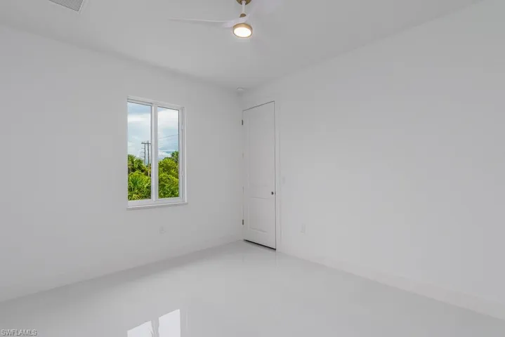 Spare room featuring tile floors, ceiling fan, and a wealth of natural light