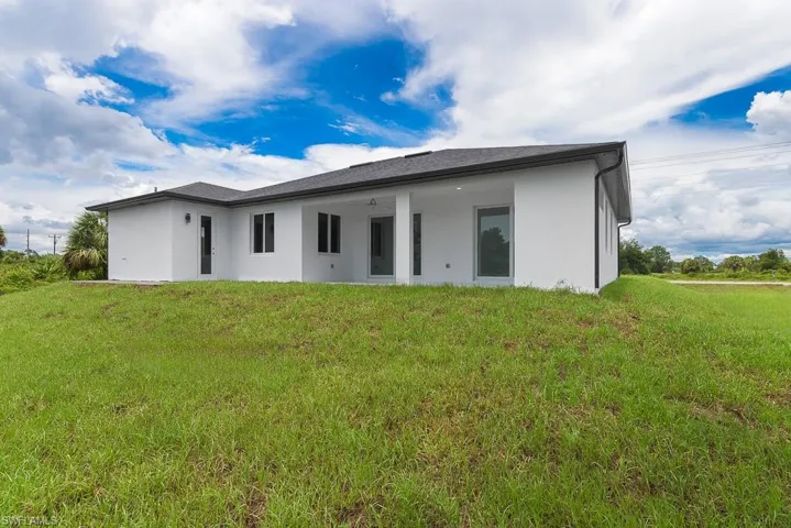 Back of property featuring ceiling fan and a lawn