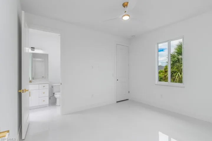 Unfurnished bedroom with tile flooring, connected bathroom, and ceiling fan