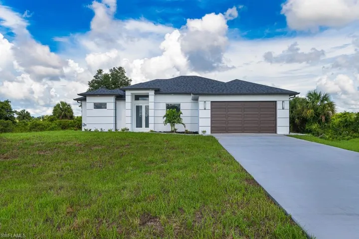 View of front of home with a garage and a front lawn