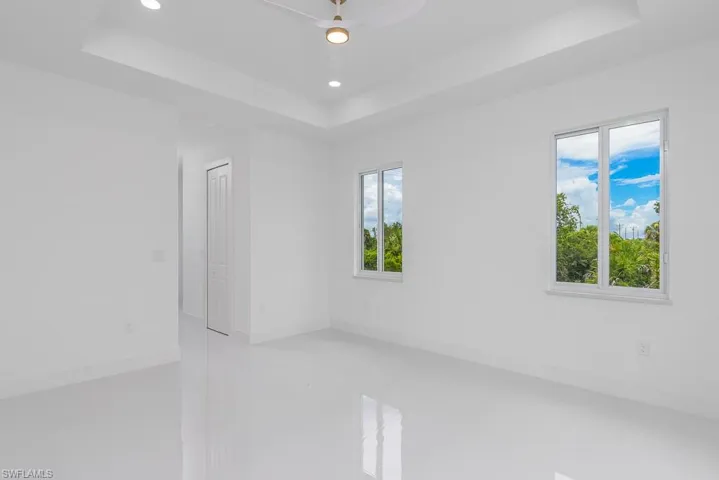 Tiled spare room featuring ceiling fan and a tray ceiling