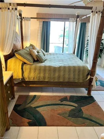 Four-poster bed with canopy drapes, wicker headboard, and a bamboo-look nightstand