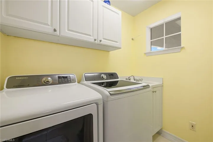 Clothes washing area with cabinets, washer and dryer, and sink