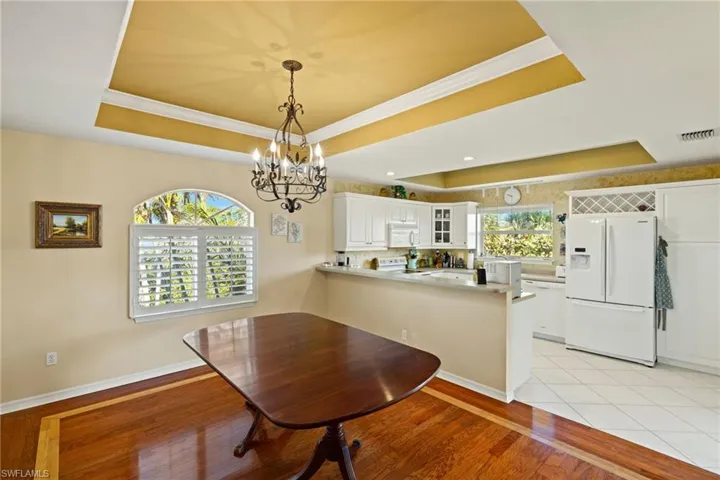 Dining room with a raised ceiling, crown molding, a healthy amount of sunlight, and light hardwood / wood-style floors