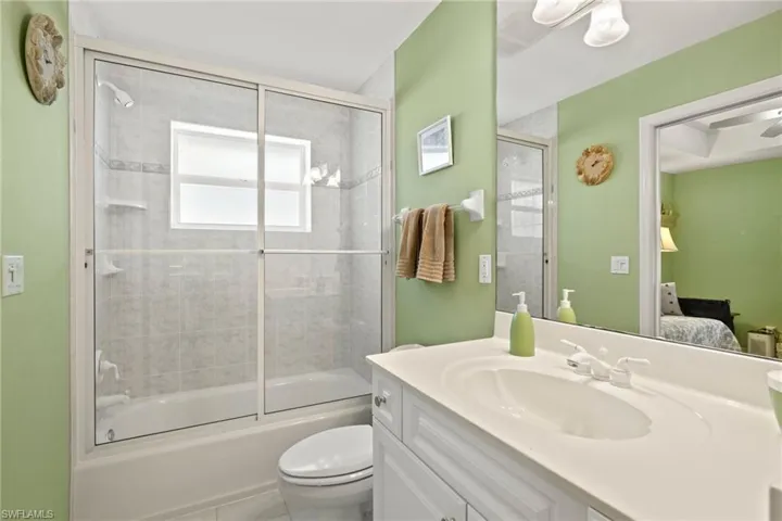 Full bathroom featuring shower / bath combination with glass door, vanity, and toilet