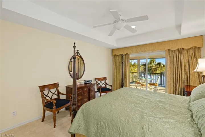 Carpeted bedroom with ceiling fan, a tray ceiling, and access to outside