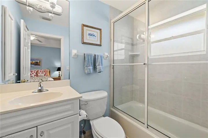 Full bathroom with shower / bath combination with glass door, vanity, and toilet