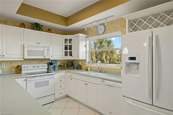 Kitchen featuring white cabinetry, sink, and white appliances