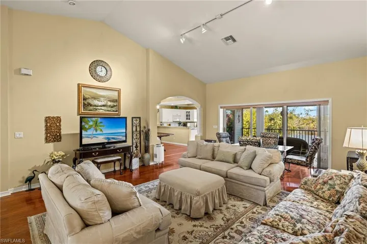 Living room with rail lighting, hardwood / wood-style floors, and high vaulted ceiling