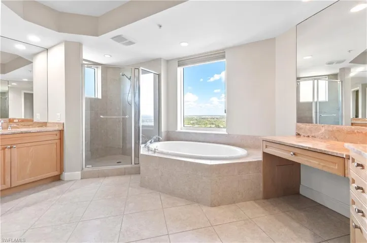 Bathroom featuring vanity, a bath, a stall shower, light tile patterned flooring, and recessed lighting
