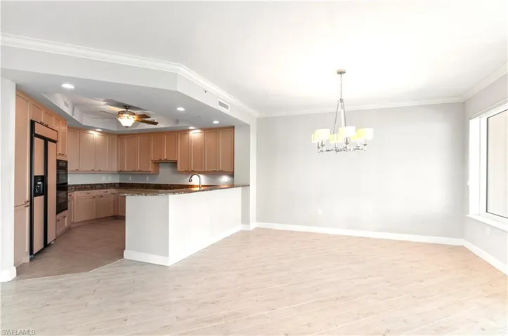Kitchen with ceiling fan, a peninsula, hanging lights, paneled built in refrigerator, and ornamental molding