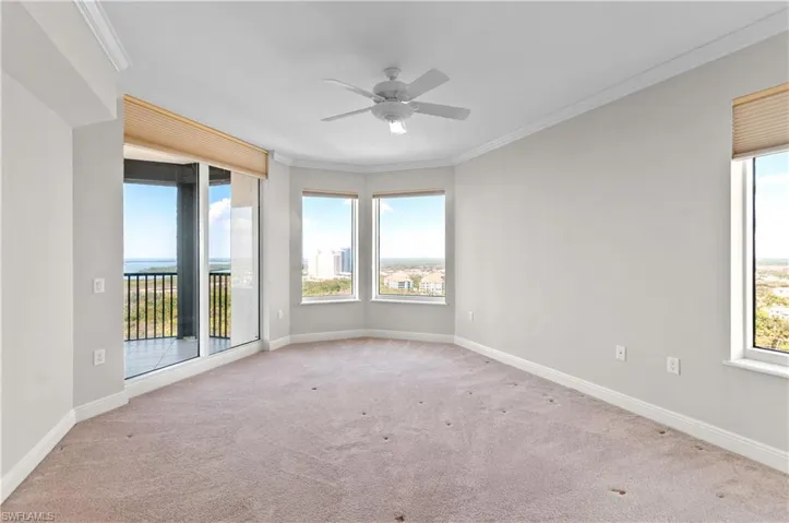 Empty room with crown molding, ceiling fan, light colored carpet, and plenty of natural light