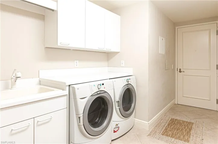 Laundry area with light tile patterned floors, cabinet space, and washing machine and dryer