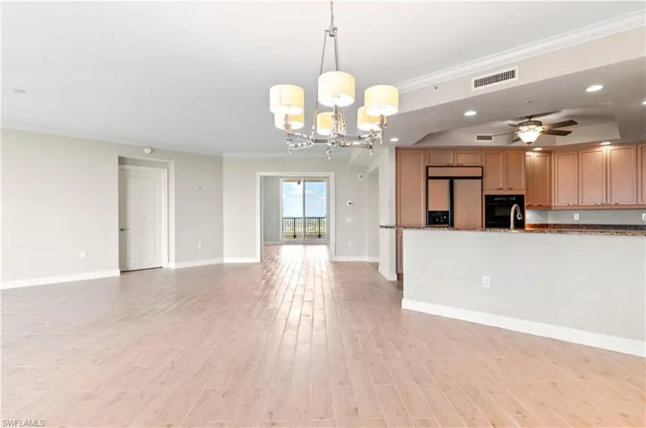 Kitchen with crown molding, a ceiling fan, open floor plan, hanging lights, and light wood-style flooring
