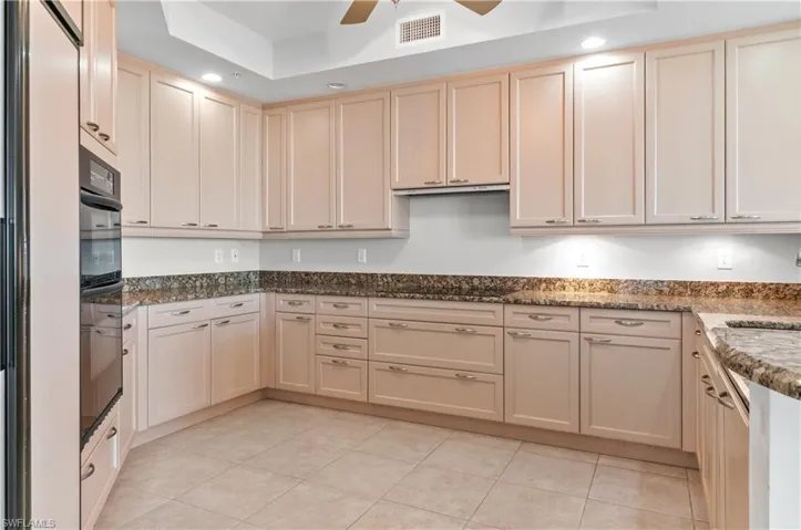 Kitchen featuring a ceiling fan, dark stone counters, cream cabinetry, black appliances, and light tile patterned flooring