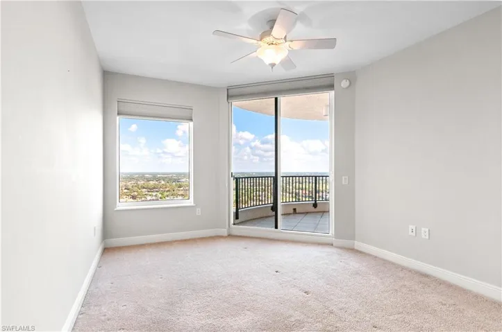 Empty room featuring a ceiling fan, healthy amount of natural light, and light carpet