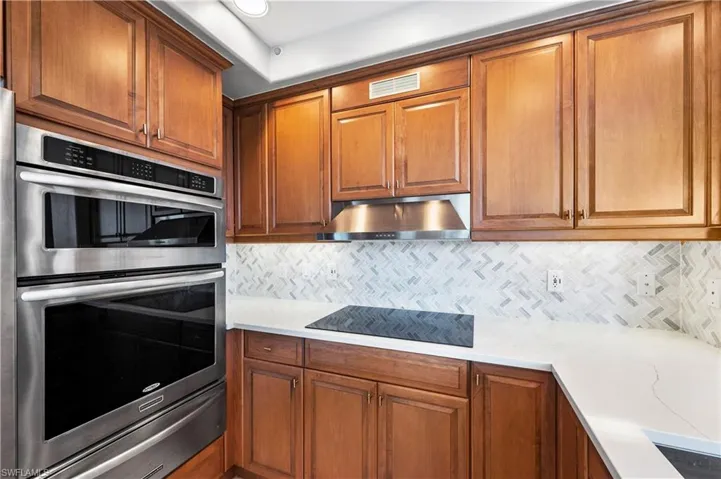 Kitchen with double oven, wood finish cabinets, a warming drawer, and black electric stovetop