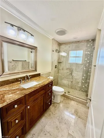 2nd Bathroom featuring a rich wood-finish vanity with a stone countertop and undermount sink
