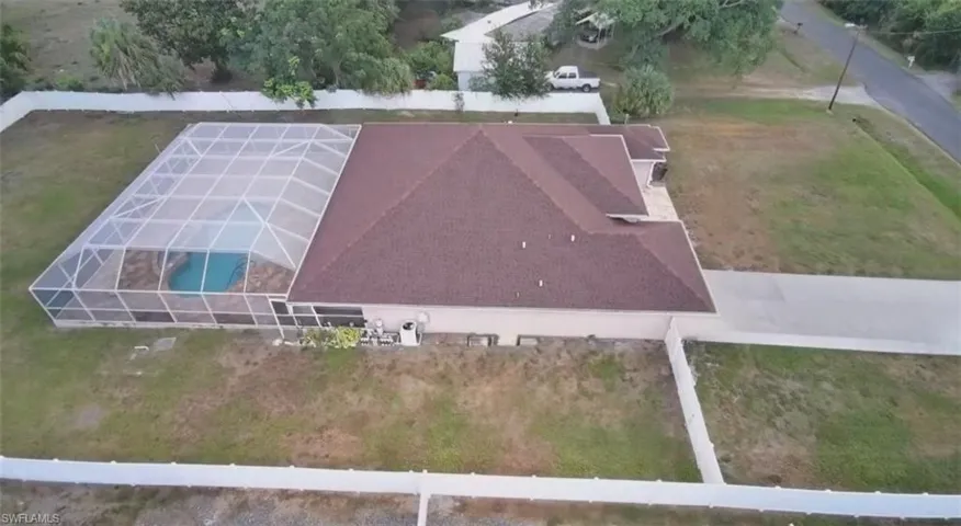 Screened-in pool enclosure featuring a rectangular pool and paved pool deck