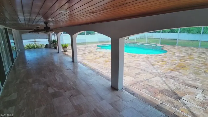 Expansive covered patio featuring a wood-finish ceiling, multiple ceiling fans, and large format tile flooring