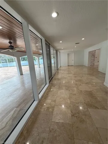 Expansive interior space featuring large format stone tile flooring, recessed ceiling lighting, and a wall of sliding glass doors