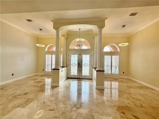 Grand entry foyer featuring polished stone flooring and decorative columns