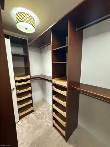Master bedroom Custom closet system featuring dark wood-finish shelving and light wood-finish pull-out drawers