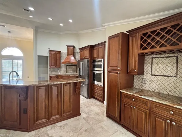 Kitchen featuring extensive wood cabinetry, granite countertops, tile flooring, stainless steel appliances, and recessed lighting