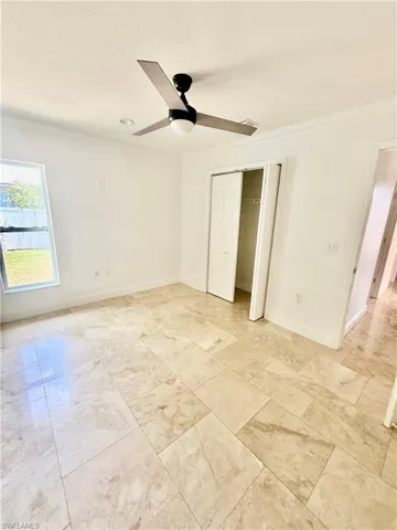 Spacious guest room featuring large format tile flooring, a modern ceiling fan, recessed lighting, and a bi-fold closet