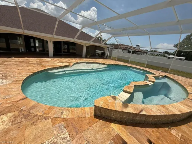 Screened outdoor area featuring a freeform swimming pool and integrated spa