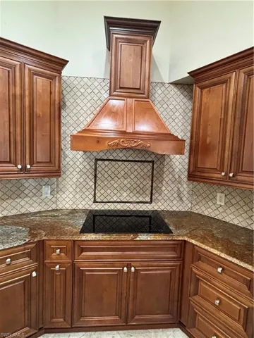 Custom wood range hood with carved accents over a black induction cooktop