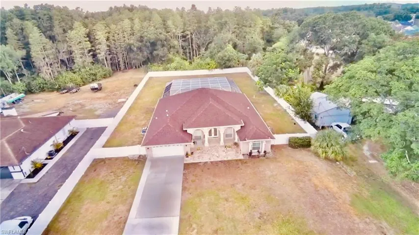 Gable-roof property featuring a screened pool enclosure, a concrete driveway, and a white fence