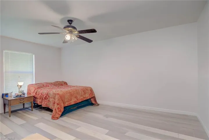 Bedroom with a ceiling fan, baseboards, and light wood-type flooring