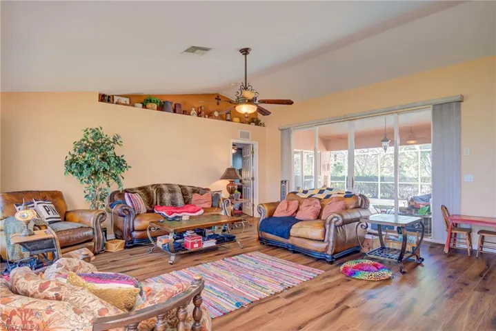Living room featuring lofted ceiling, ceiling fan, wood finished floors, and visible vents