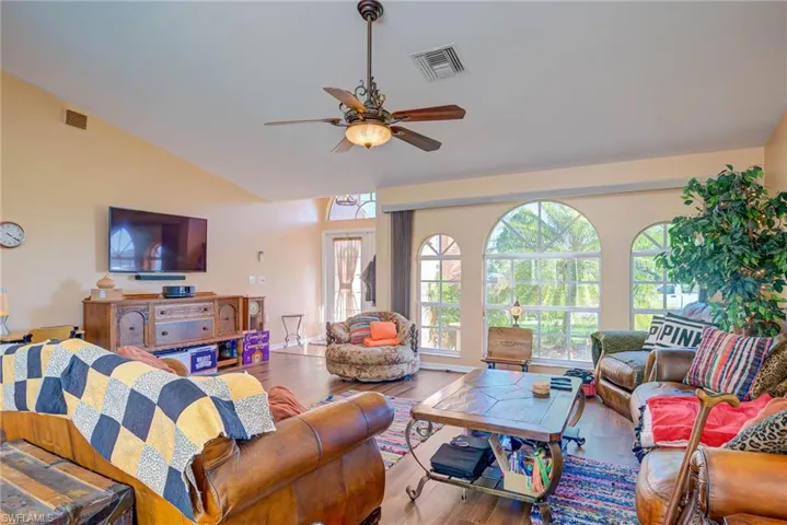 Living room featuring visible vents, wood finished floors, ceiling fan, and vaulted ceiling