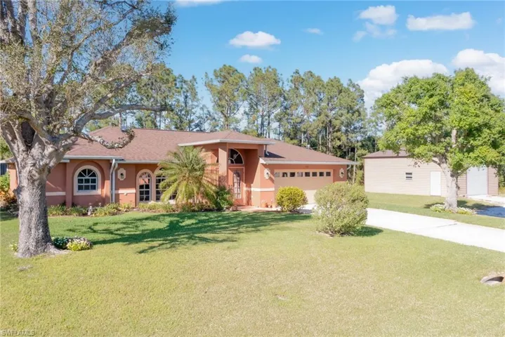 View of front of home with a front yard, driveway, stucco siding, and an attached garage
