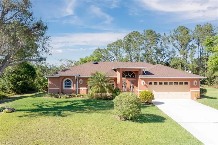 View of front of home with stucco siding, an attached garage, and a front yard
