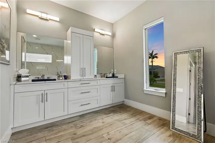 Bathroom with double vanity, wood finished floors, and a marble finish shower