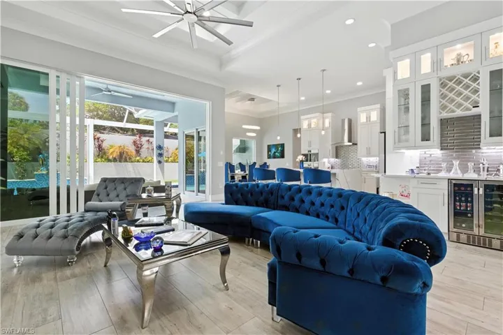 Living area with wine cooler, a ceiling fan, ornamental molding, light wood-style flooring, and recessed lighting