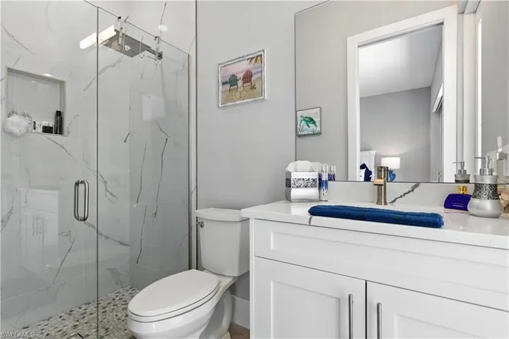 Full bathroom featuring a marble finish shower and vanity