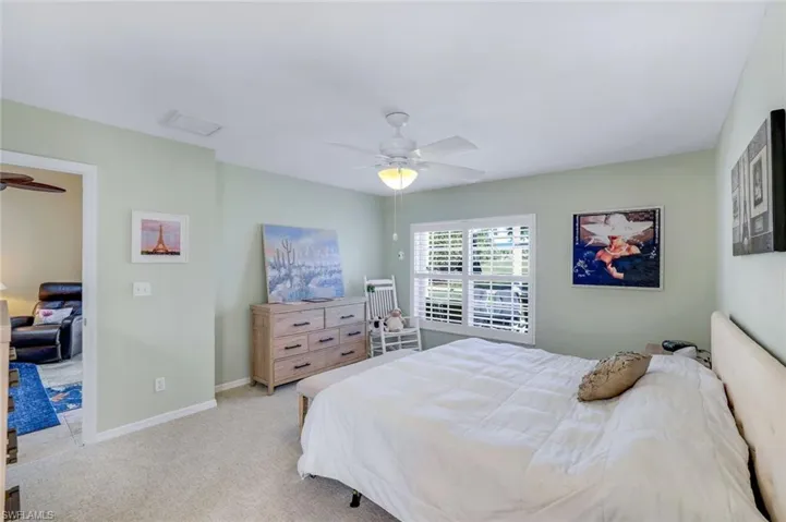 Bedroom with light carpet, ceiling fan, and baseboards
