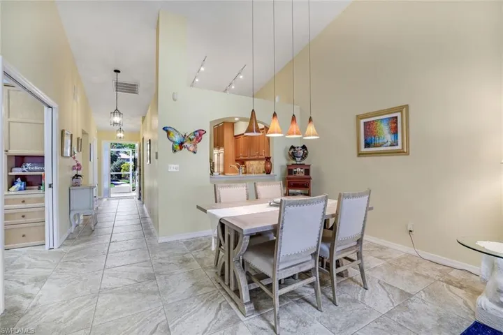 Dining space featuring high vaulted ceiling, track lighting, visible vents, and baseboards