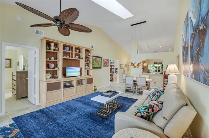 Living room featuring a skylight, arched walkways, visible vents, ceiling fan, and high vaulted ceiling