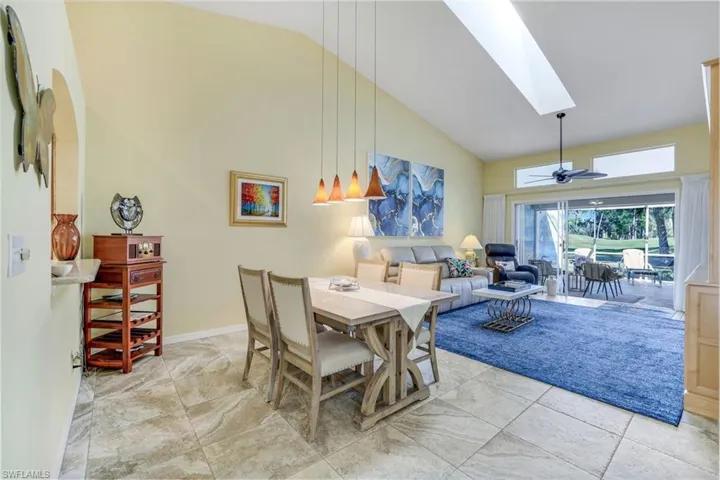 Dining space featuring high vaulted ceiling, a skylight, a ceiling fan, and baseboards