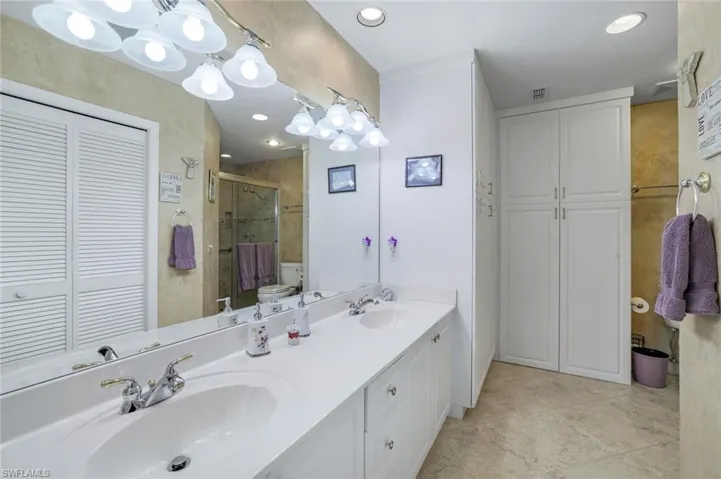Bathroom with a closet, a sink, visible vents, and a stall shower