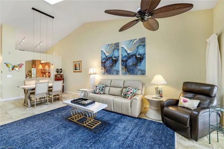 Living room featuring a ceiling fan, vaulted ceiling, and baseboards