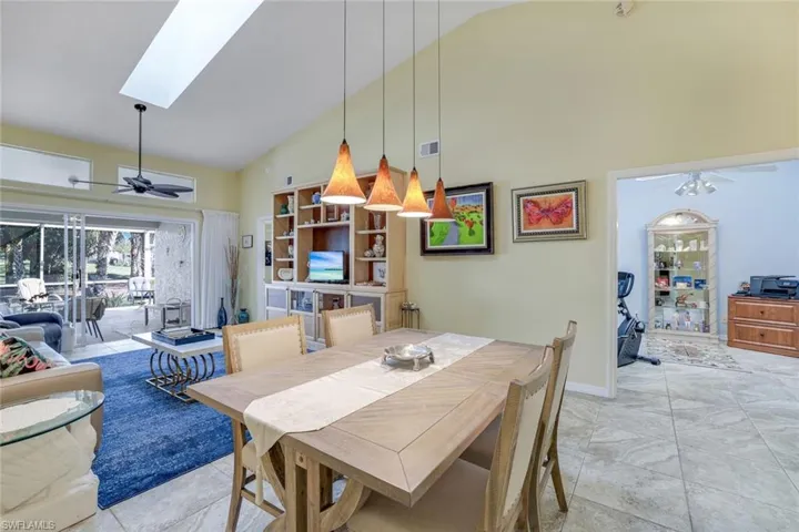 Dining area featuring a skylight, visible vents, ceiling fan, high vaulted ceiling, and baseboards