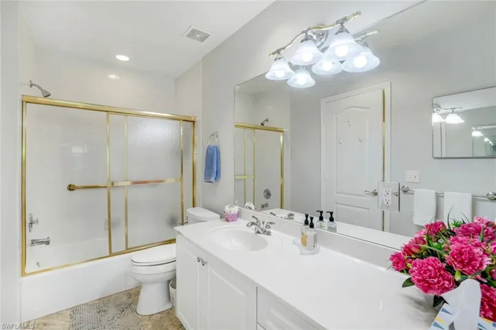 Bathroom with visible vents, vanity, toilet, and combined bath / shower with glass door