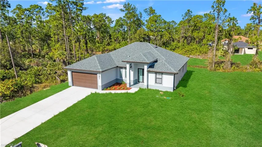 View of front of property with a front lawn, stucco siding, a shingled roof, and driveway